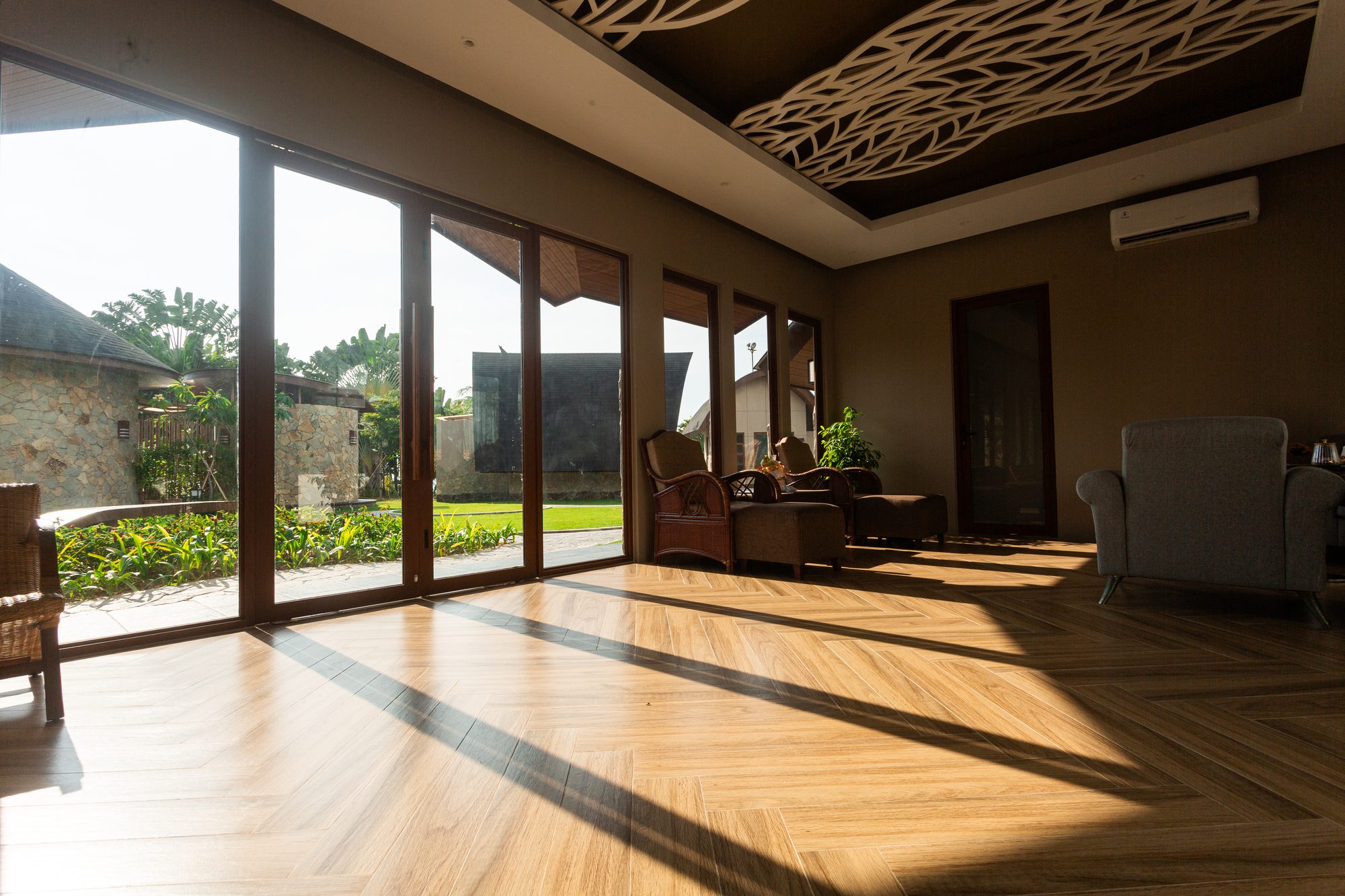 The lounge beneath its carved leaf-pattern timber ceiling, with garden views beyond