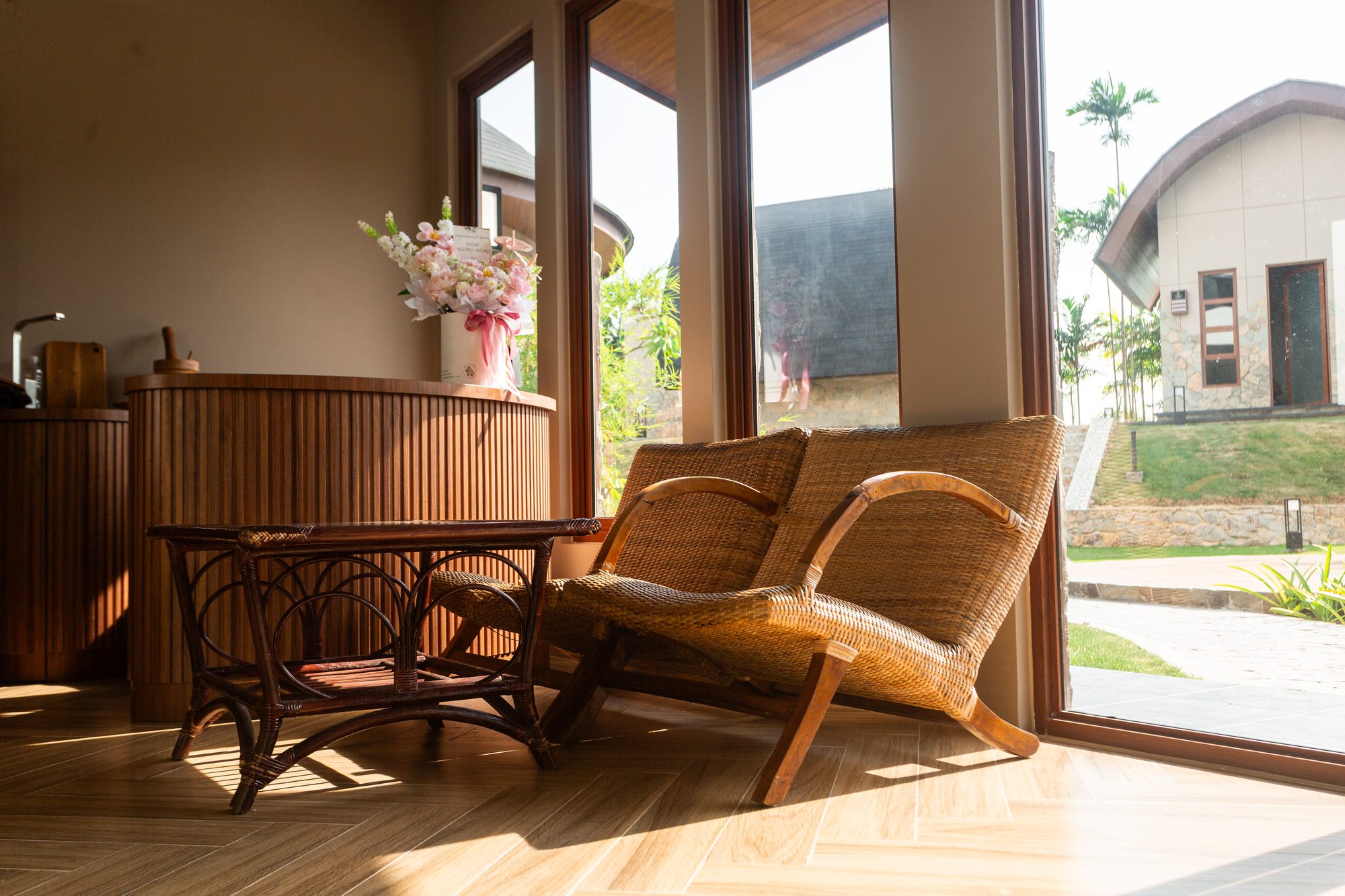 Rattan armchairs and a cane table in the reception lounge, with fresh flowers on the counter