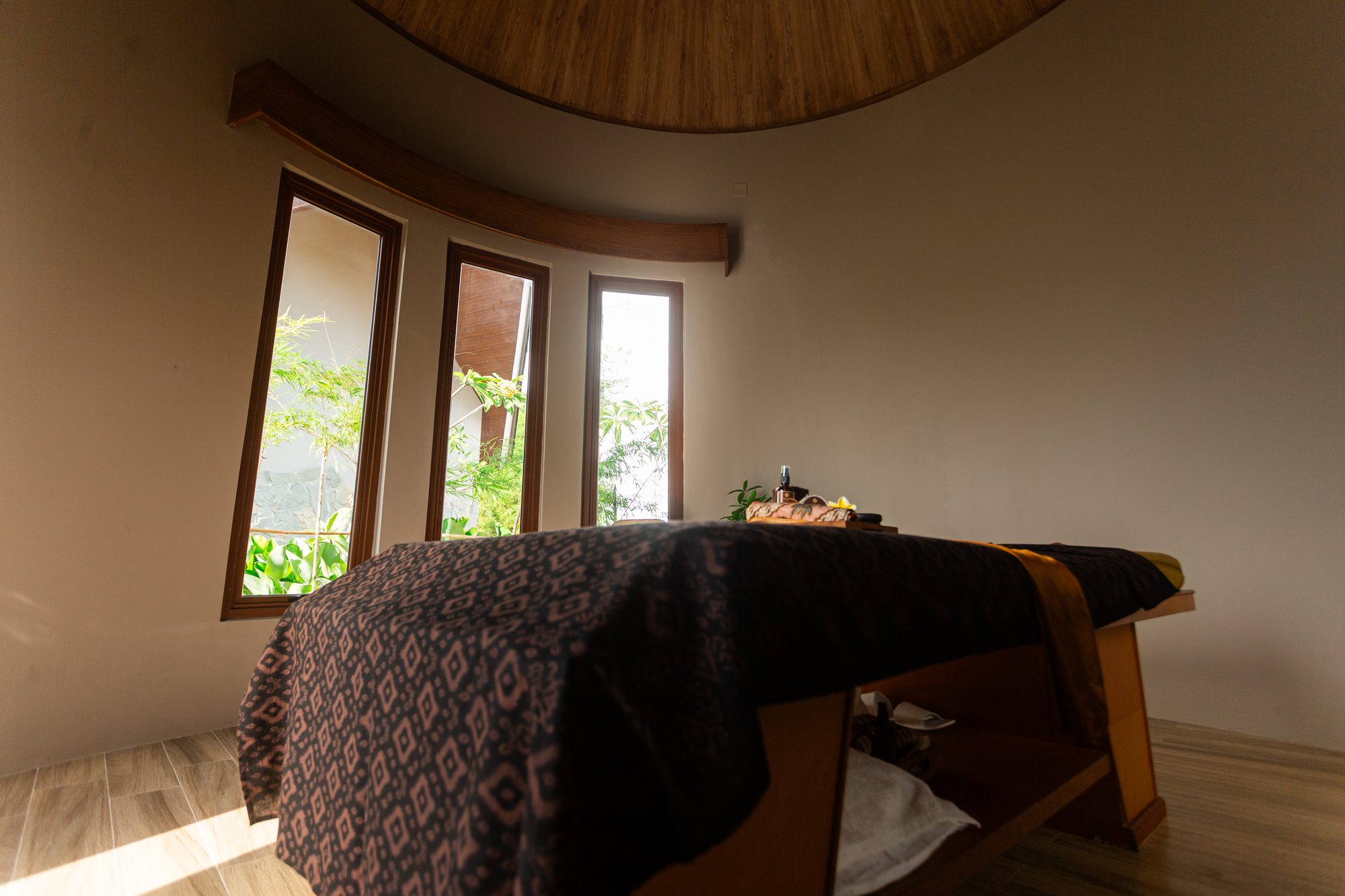 A treatment bed dressed in Indonesian textile beneath the room's timber dome
